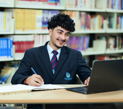 Student studying in a library with a laptop