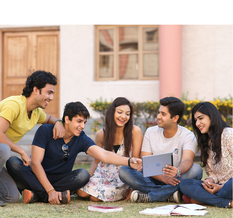 Students sitting on grass, looking at a tablet