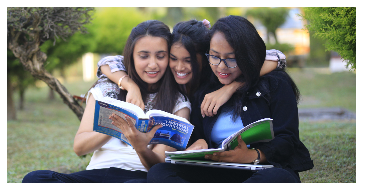 Three female students studying together outdoors with engineering textbooks